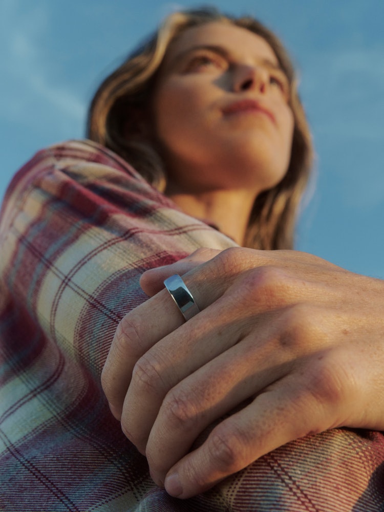 A person looking upward outdoors while wearing Auro Ring 5 in silver
